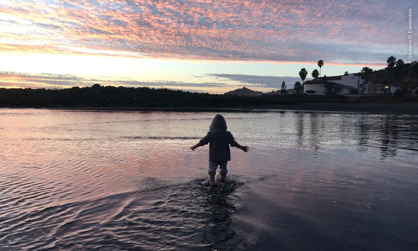 Niño a contraluz en el agua de la ensenada que se forma en San Miguel cuando sube la marea.